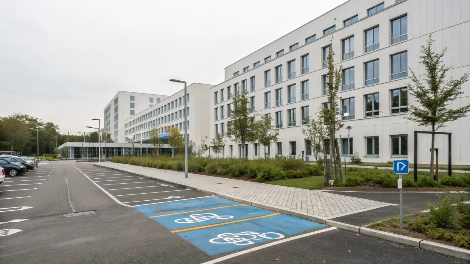 Besucherparkplatz an einem modernen Klinikgebäude (illustrative Szene)